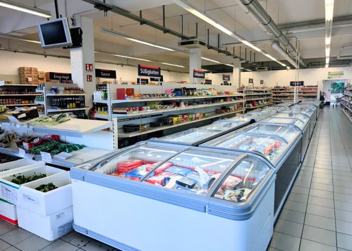 Blick in die Gänge eines asiatischen Supermarkts mit gut gefüllten Regalen für Lebensmittel und Soßen.